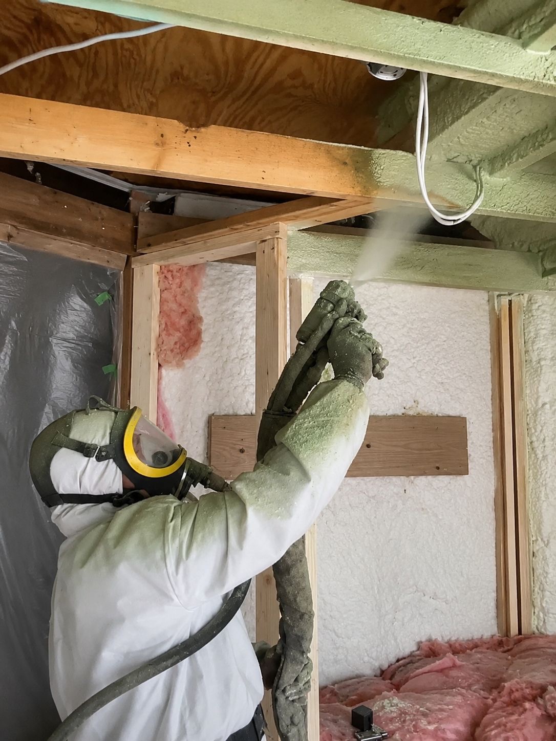 Insulation technician applying spray foam inside a Manitoba home